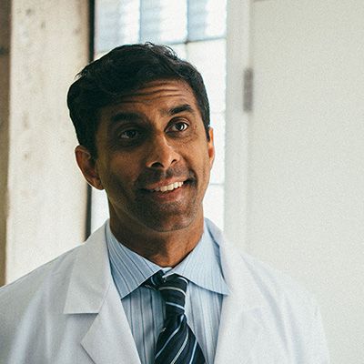 Photo of trustworthy-looking doctor in lab coat, smiling to camera.