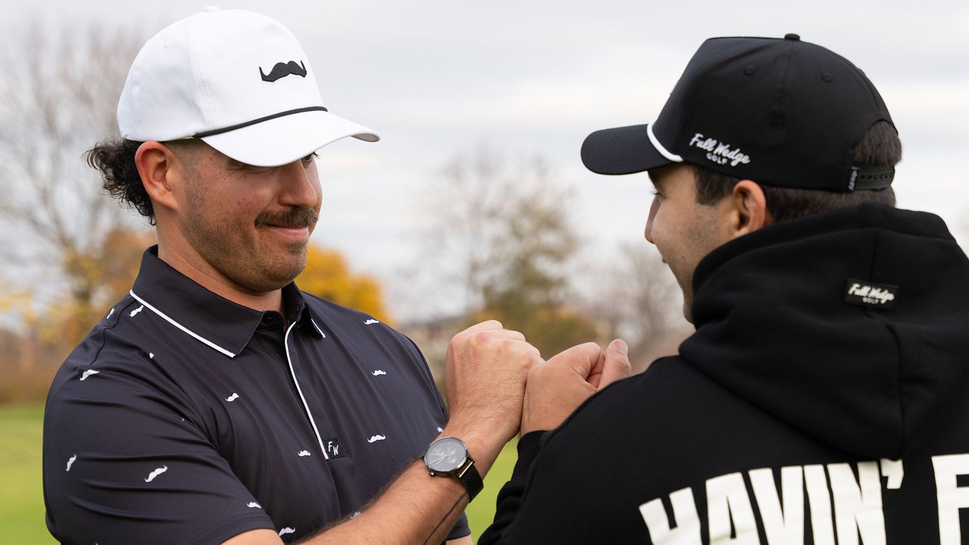 Photo of two golfers on a course, donning exceptional moustaches.